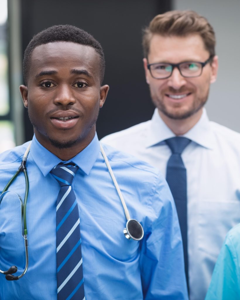 smiling-medical-team-standing-together-hospital-corridor-min